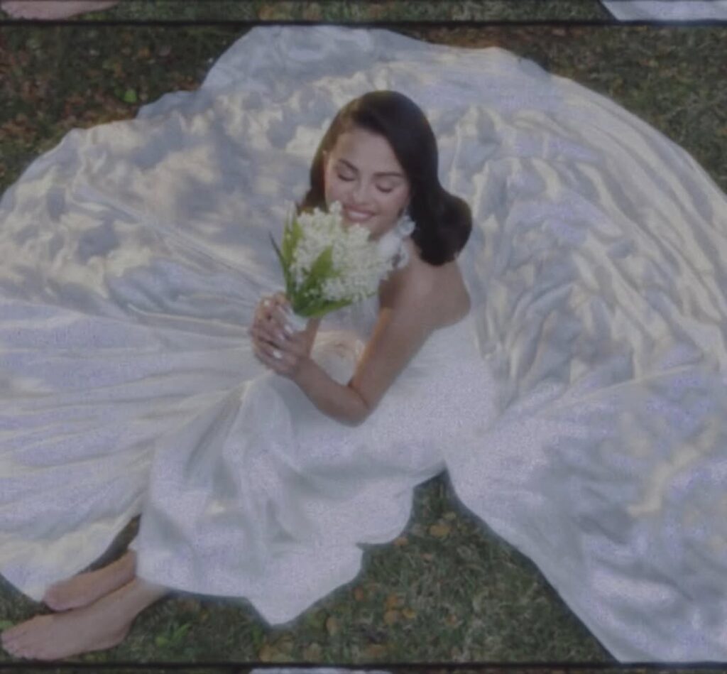 bride smiling while seated in wedding gown holding bouquet outdoors