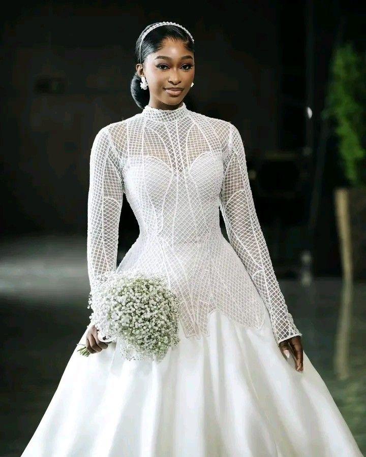 A long-sleeve wedding dress with an illusion bodice and basque waist detail, showcasing structured modern bridal fashion.