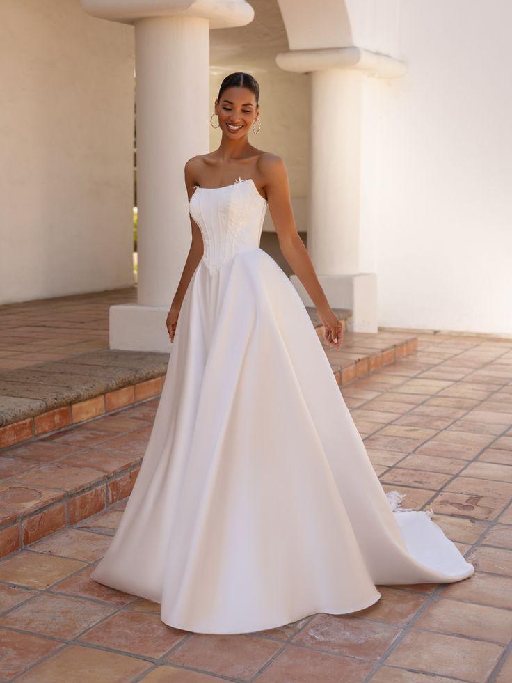 A strapless basque waist wedding dress featuring a full ball gown skirt and clean, modern bridal silhouette.